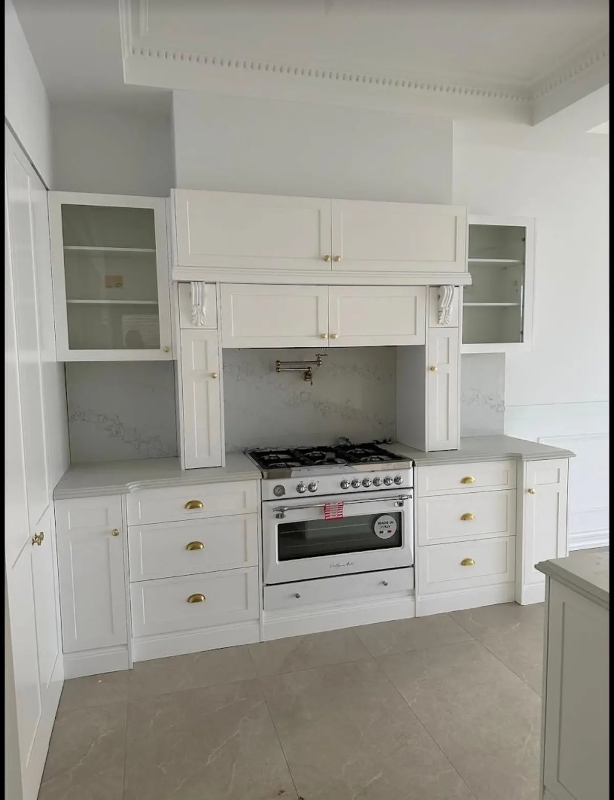 Hamptons style white kitchen with a freestanding cooker, rangehood surround and glass display cabinets