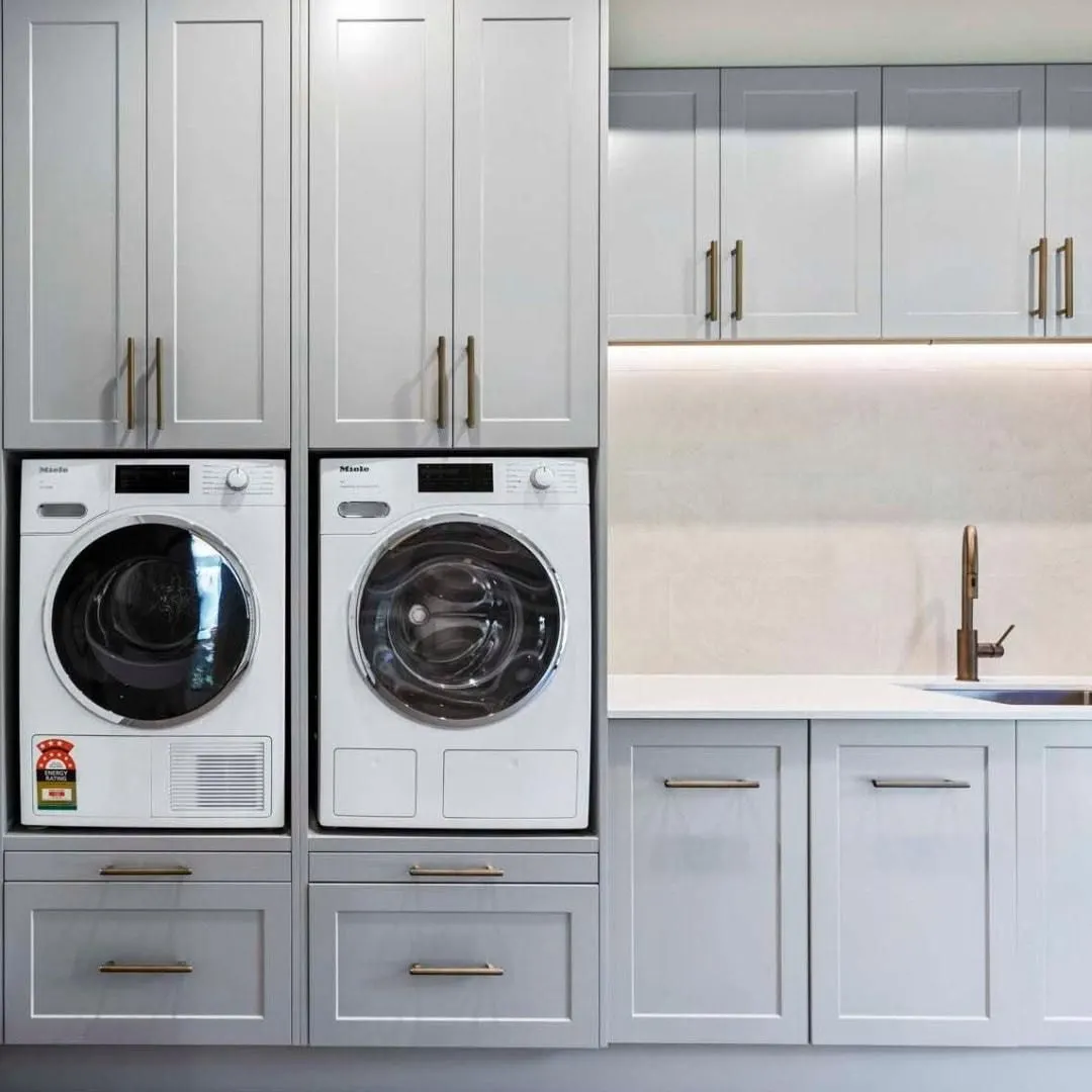 Laundry with the washer and dryer raised in tall custom cabinetry, shaker doors and a stone benchtop