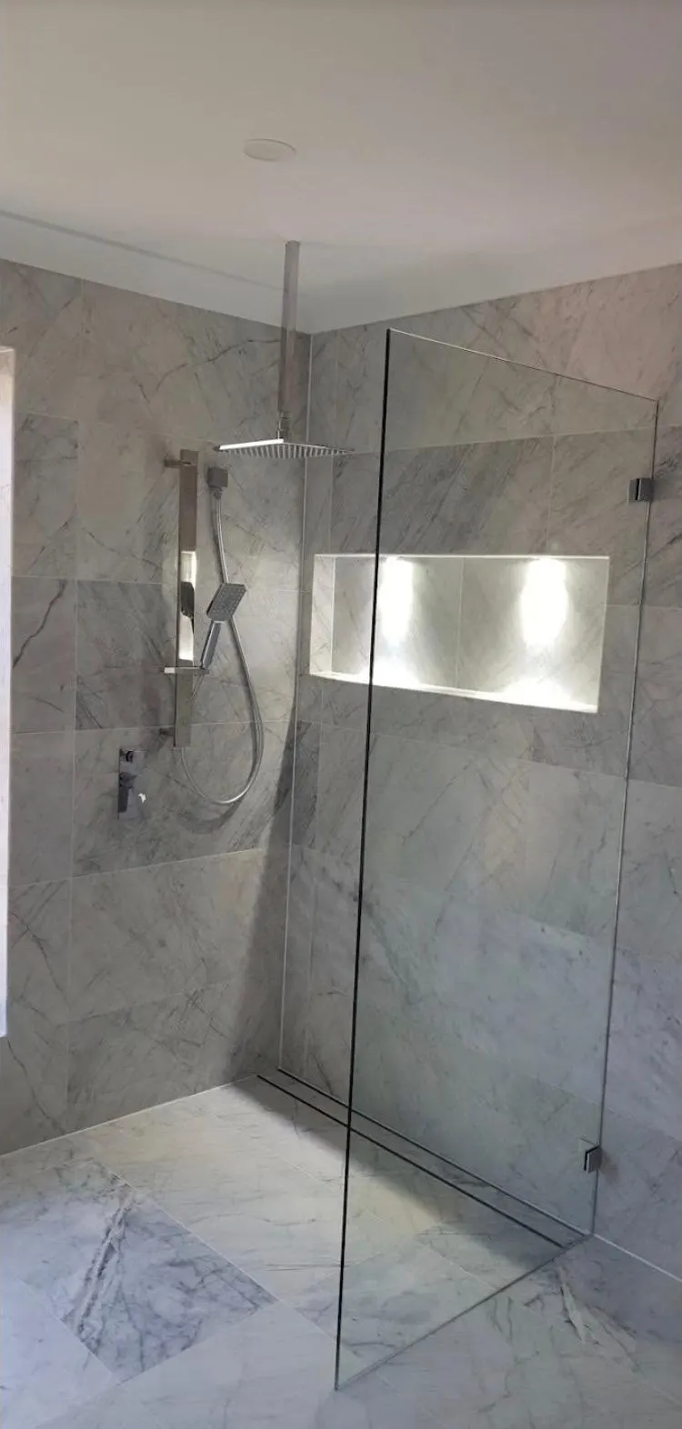 Walk in shower with grey marble look tiles, a frameless glass screen and an LED lit shower niche