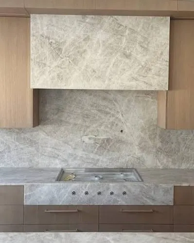 Kitchen with a full height marble splashback, matching marble rangehood and timber cabinetry under the cooktop