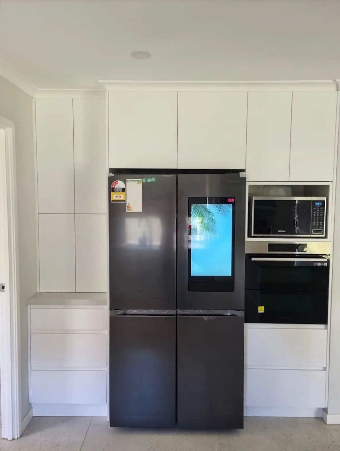 Floor to ceiling pantry and appliance cabinetry built around a fridge, wall oven and microwave